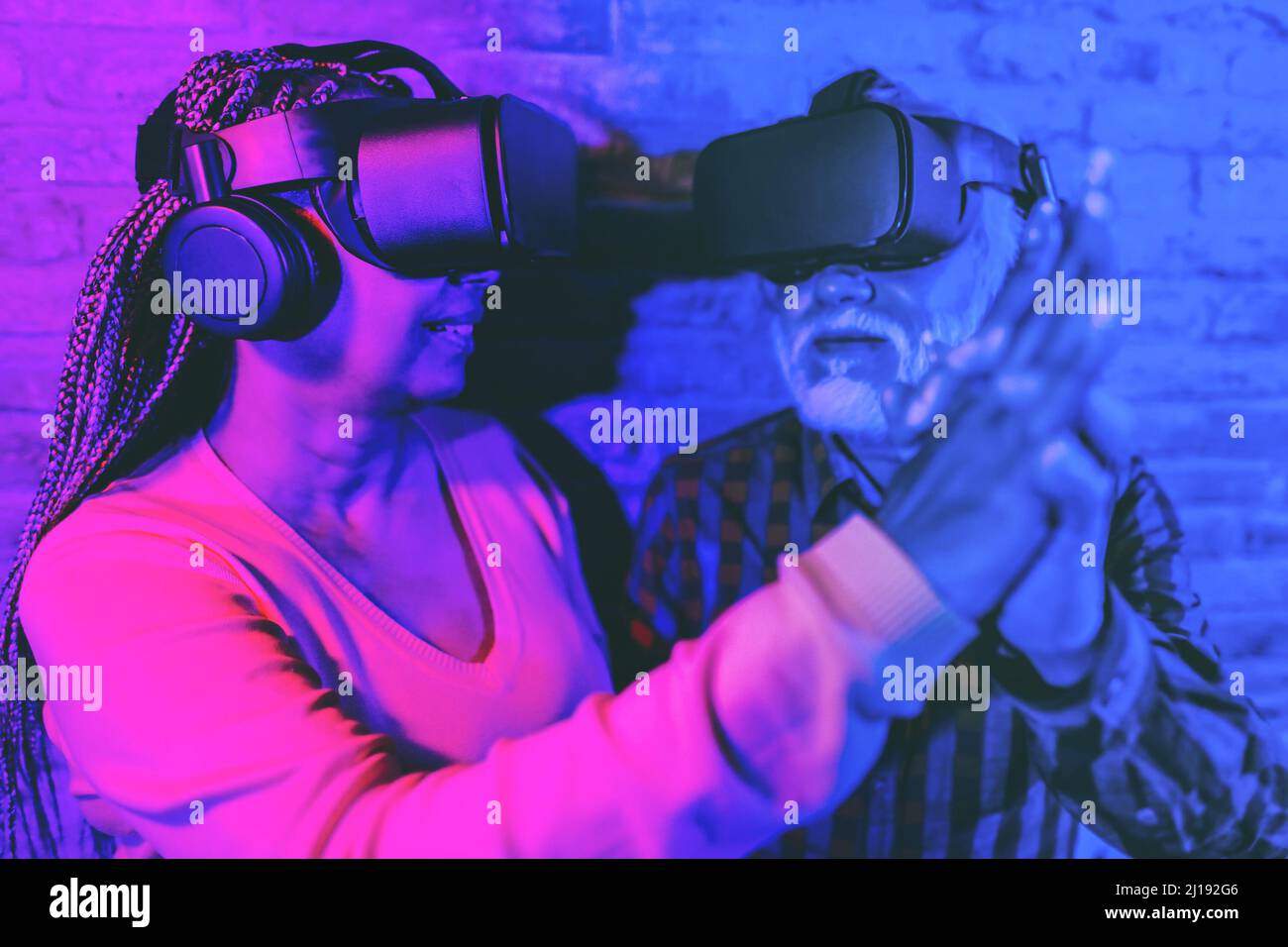 Multiracial senior friends having fun dancing while using virtual reality goggles - Focus on left headset Stock Photo