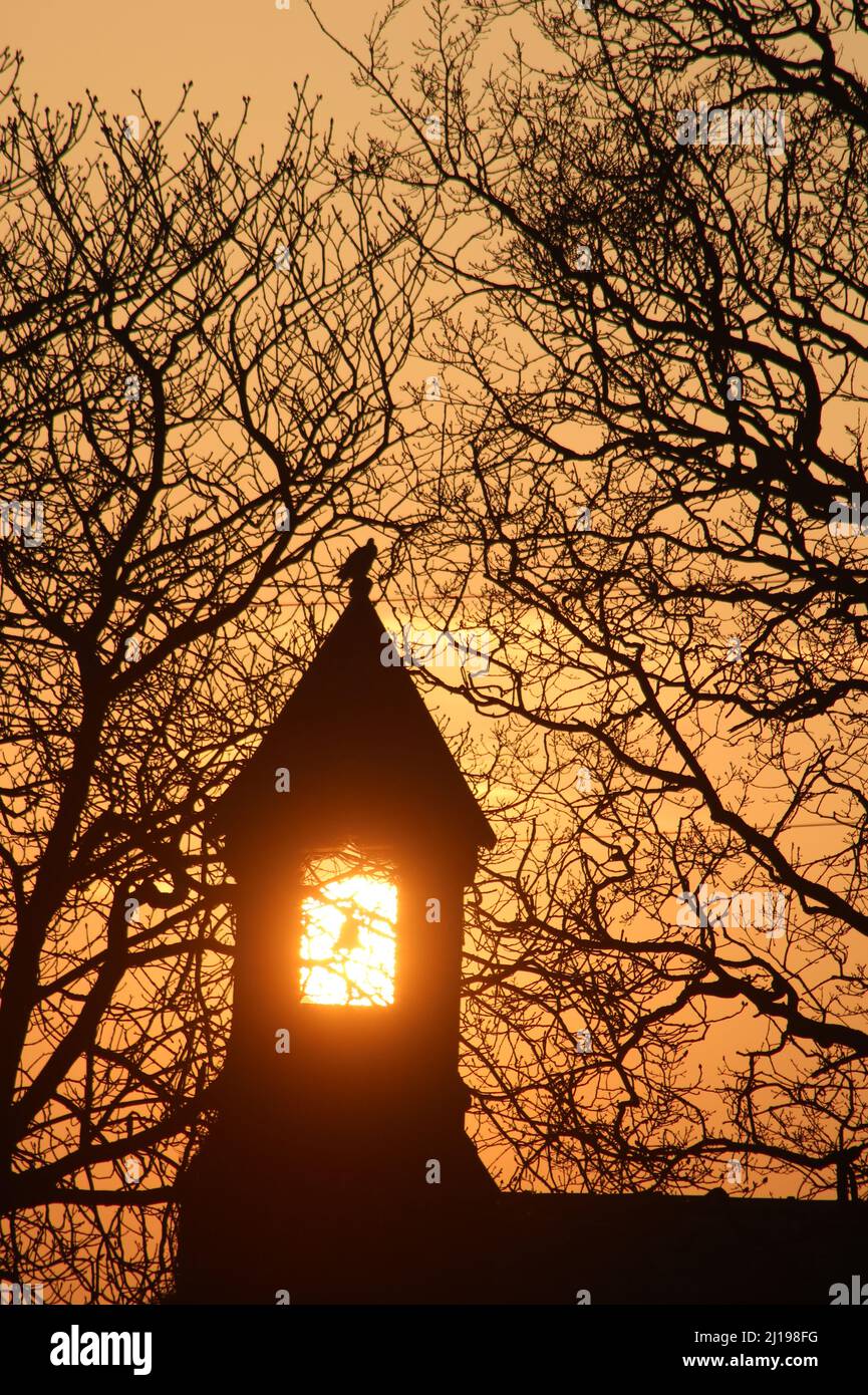Bell tower and bell at sunset with sun framed by tower at St John's C. of E. school, Pilling, Preston, Lancashire. Stock Photo