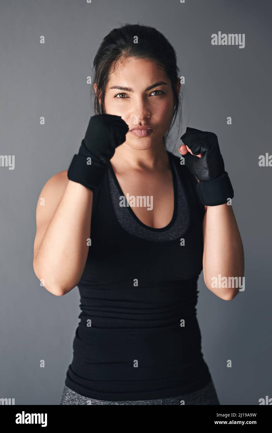 Ready for a fight. Studio shot of a female kickboxer against a gray background. Stock Photo