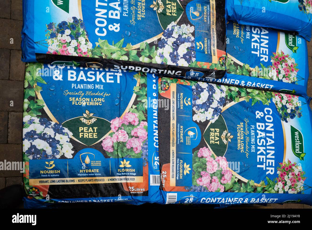 A stack of bags of Westland Brand Container and Basket Compost in a garden centre captioned
