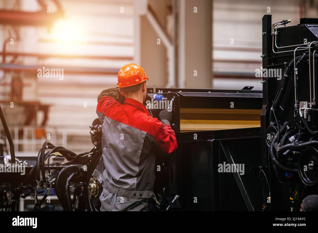 Industrial workers assembles agricultural harvester in workshop. Stock Photo