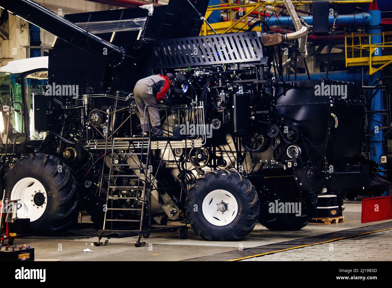 Industrial workers assembles agricultural harvester in workshop. Stock Photo