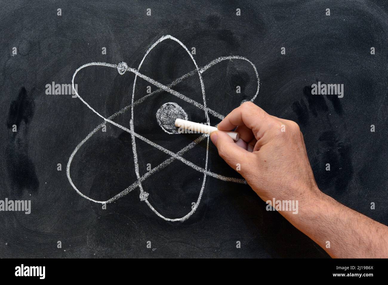 Mano señalando el símbolo del átomo dibujado con tiza en una pizarra Stock Photo