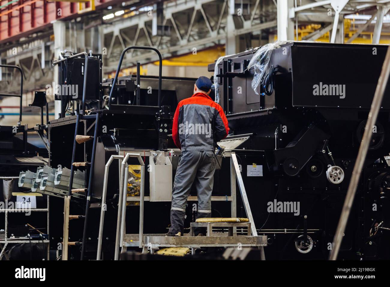 Industrial workers assembles agricultural harvester in workshop. Stock Photo
