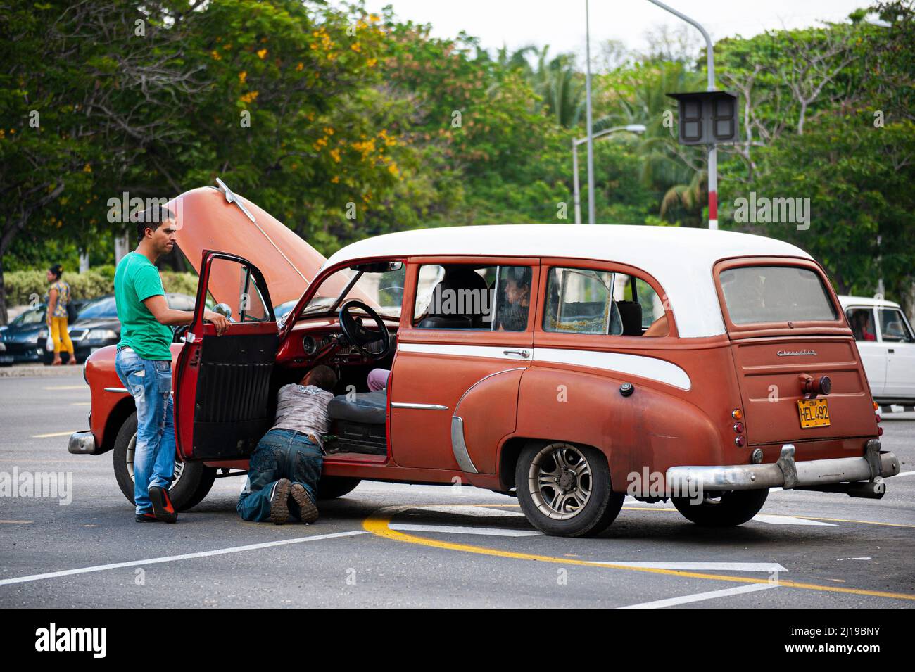 Men fix an old Cuban car on a street corner in Havana, Cuba. Stock Photo