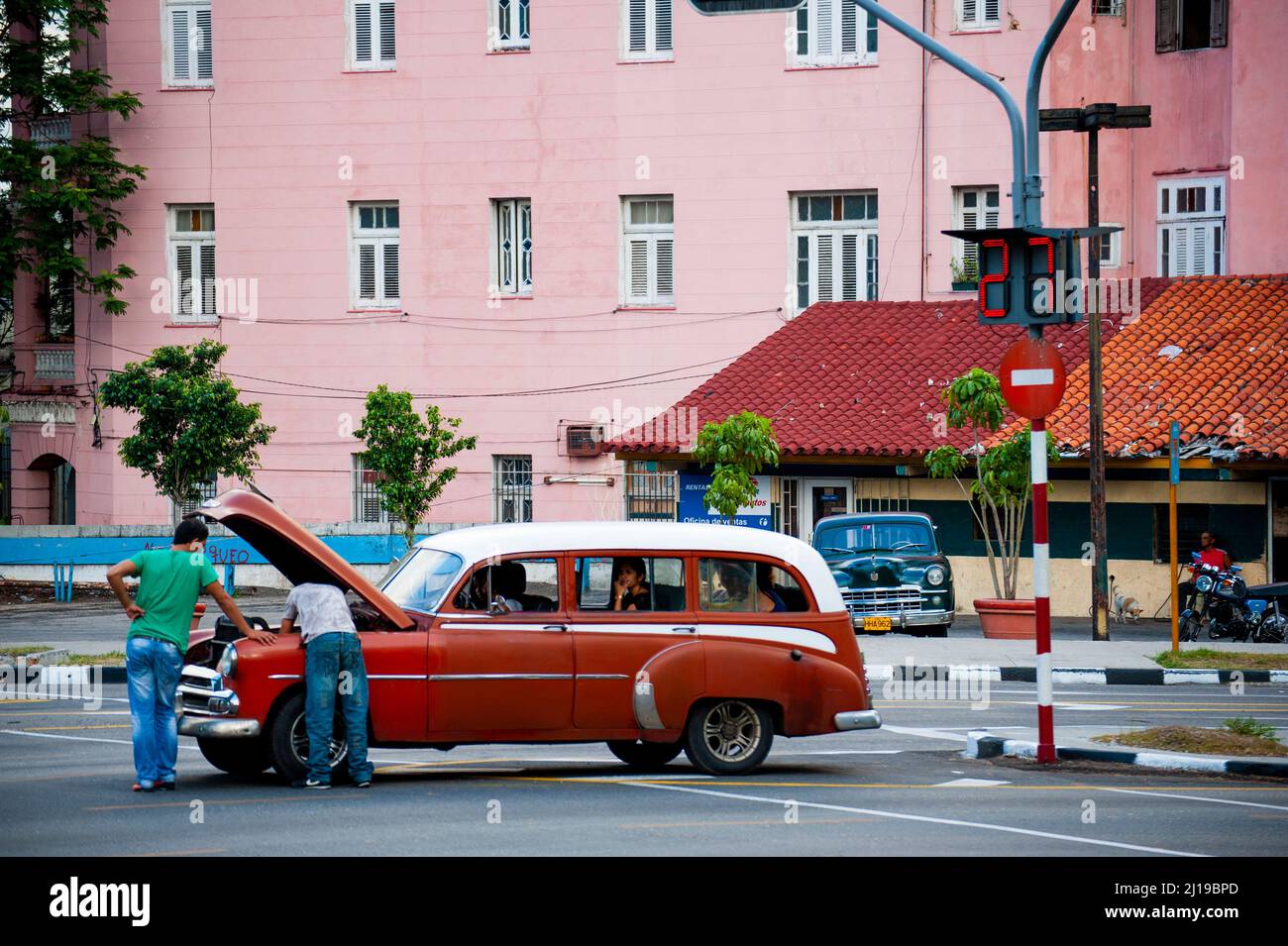 Men fix an old Cuban car on a street corner in Havana, Cuba. Stock Photo