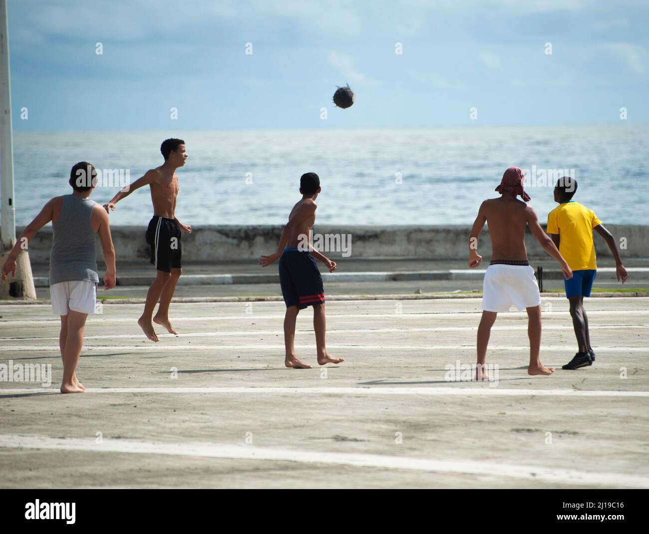 sYoung boys playing soccer on a street by the ocean in Stock Photo