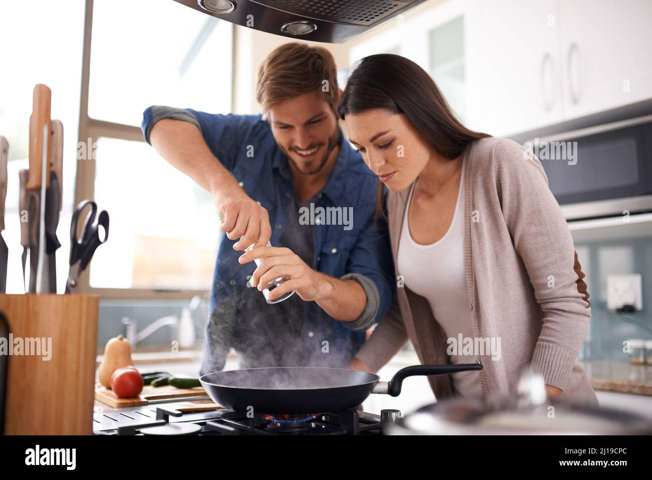 Preparing a delicious meal at home. A young couple making dinner together at home. Stock Photo