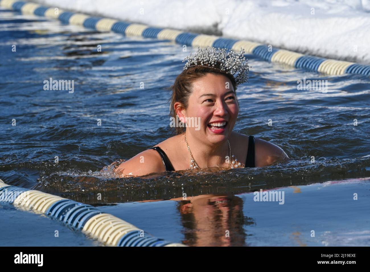 Cold water swimmers swim in the icy water of Lake Memphremagog near the Canadian board in Newport, VT, in March. Stock Photo