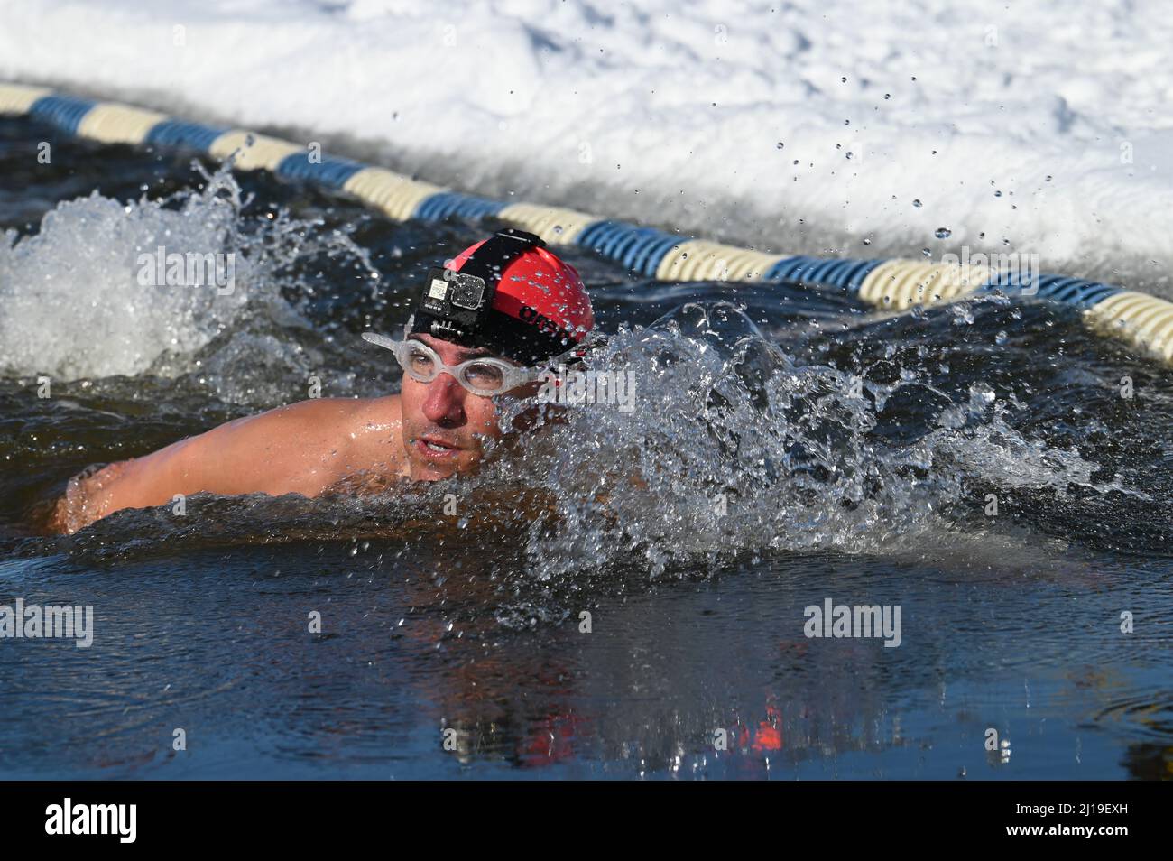 Cold water swimmers swim in the icy water of Lake Memphremagog near the Canadian board in Newport, VT, in March. Stock Photo