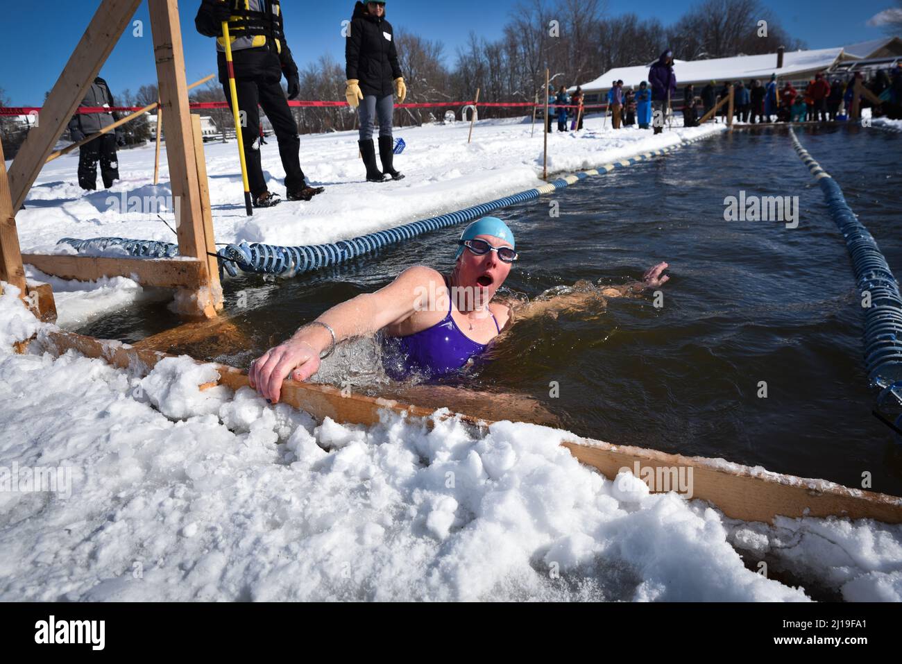 Cold water swimmers swim in the icy water of Lake Memphremagog near the Canadian board in Newport, VT, in March. Stock Photo