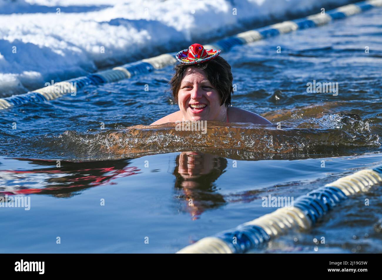Cold water swimmers swim in the icy water of Lake Memphremagog near the Canadian board in Newport, VT, in March. Stock Photo