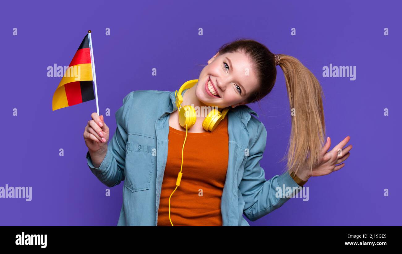 Funny Smiling Girl in casual clothes and headphones holds small German
