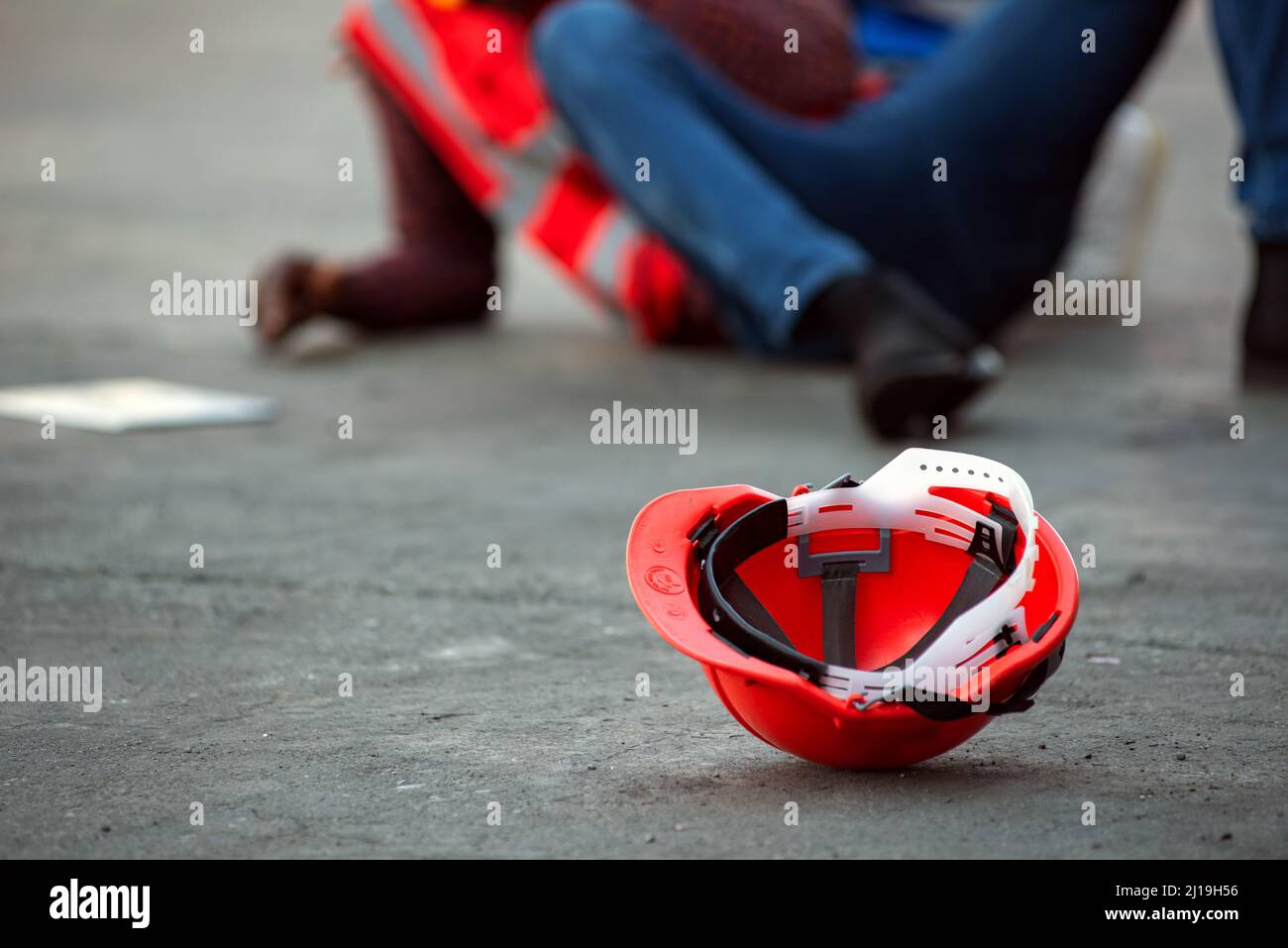 Red hard safety helmet hat for engineer on concrete ground with African