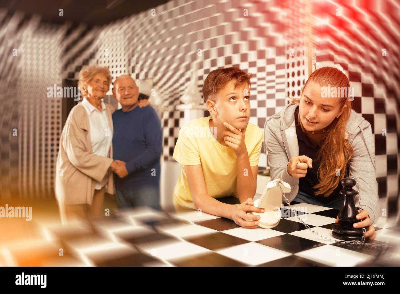 Kids solving chess riddle in escape room and grandparents watching them ...