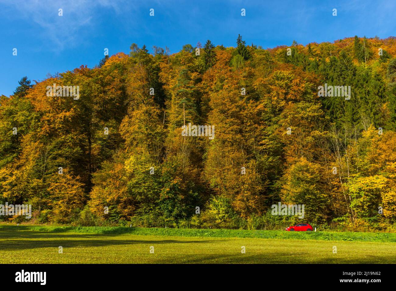 Small red car passing through beautiful autumn landscape near Graz, Styria region, Austria Stock Photo
