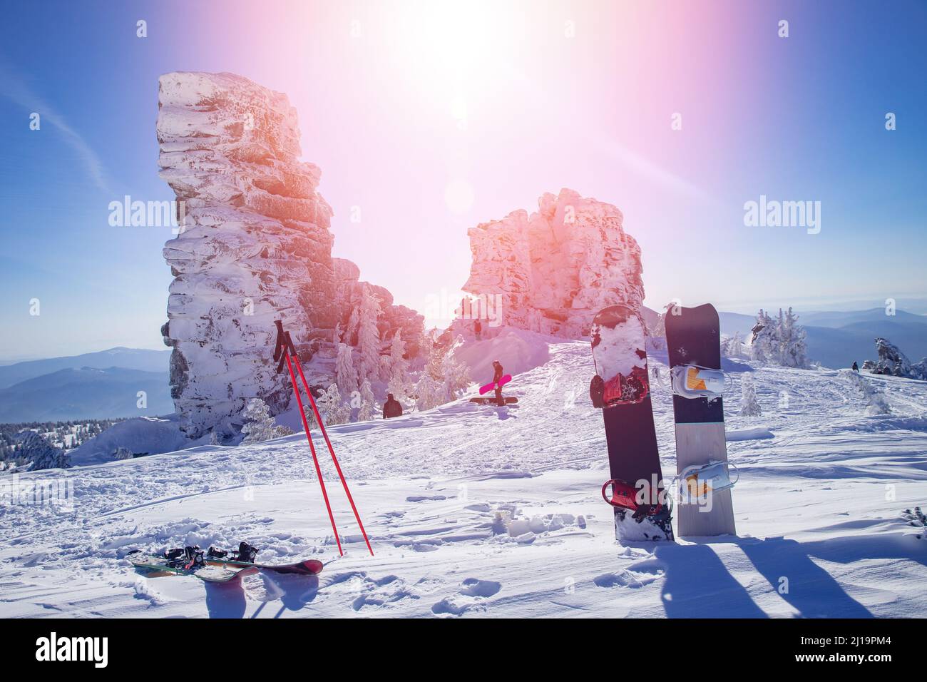 Snowboard and ski on background of snowy mountain and blue sky with sun