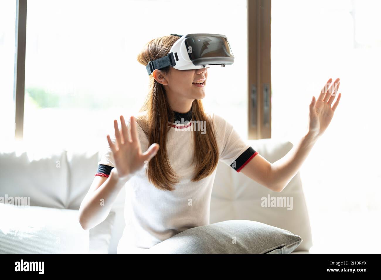 Excite asian woman playing online game with vr glasses and controller at her home Stock Photo