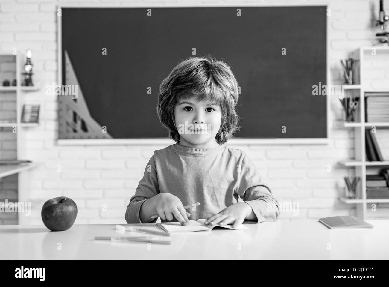 Child near chalkboard in school classroom. Child home studying and home education. Kids gets ready for school. Stock Photo