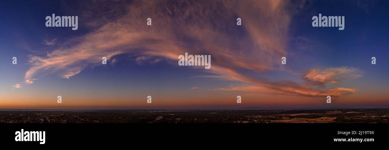Fluffy pink clouds at sunset against a deep blue sky aerial panoramic Stock Photo