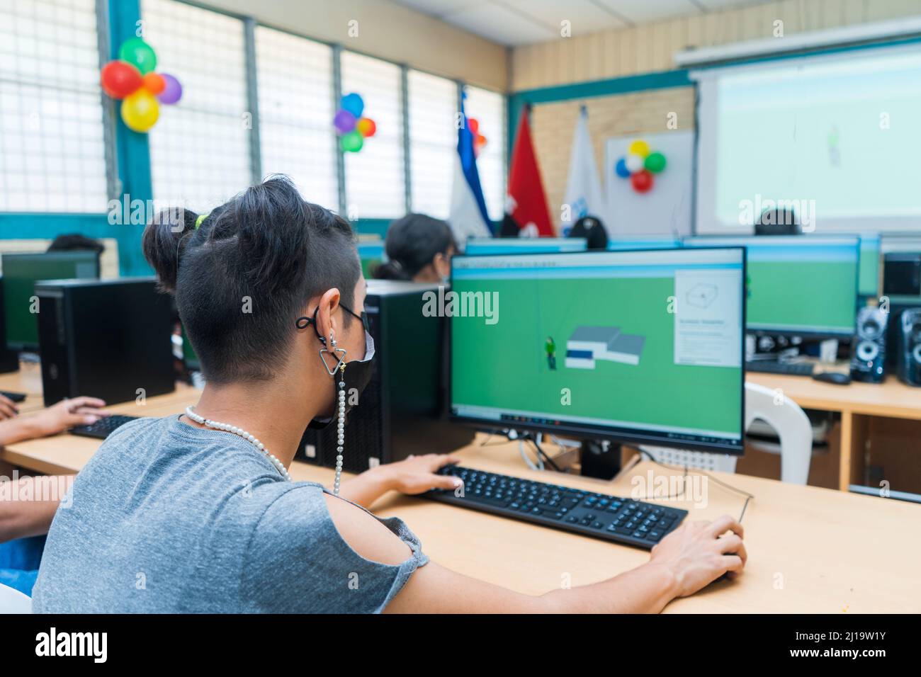 Young Central American student woman with light skin and a modern hairstyle seen from the back receives technical education Stock Photo