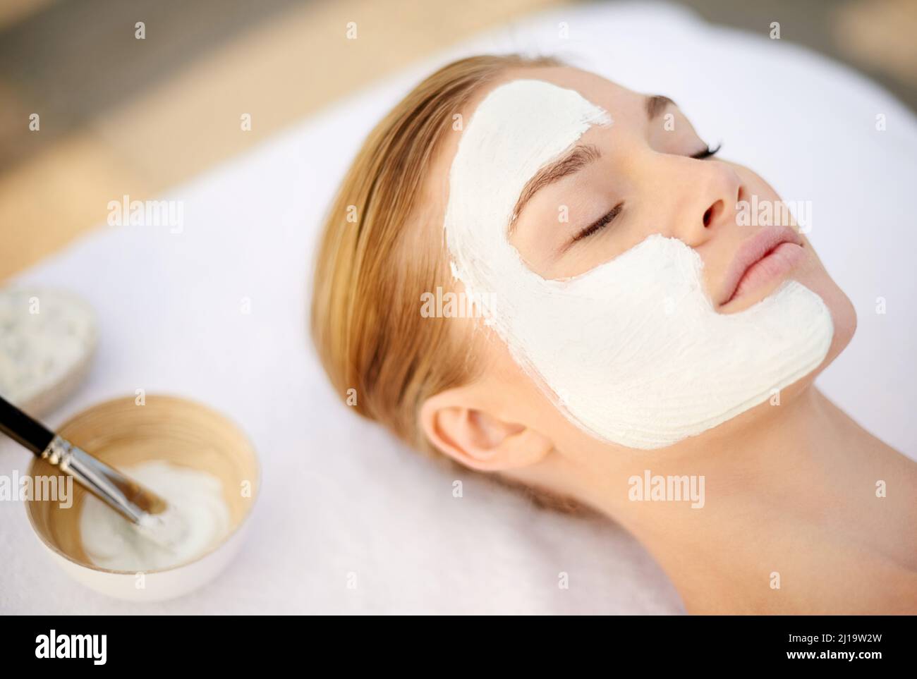 Indulging in a deep cleansing masque. Shot of a young woman getting a facial at a spa. Stock Photo