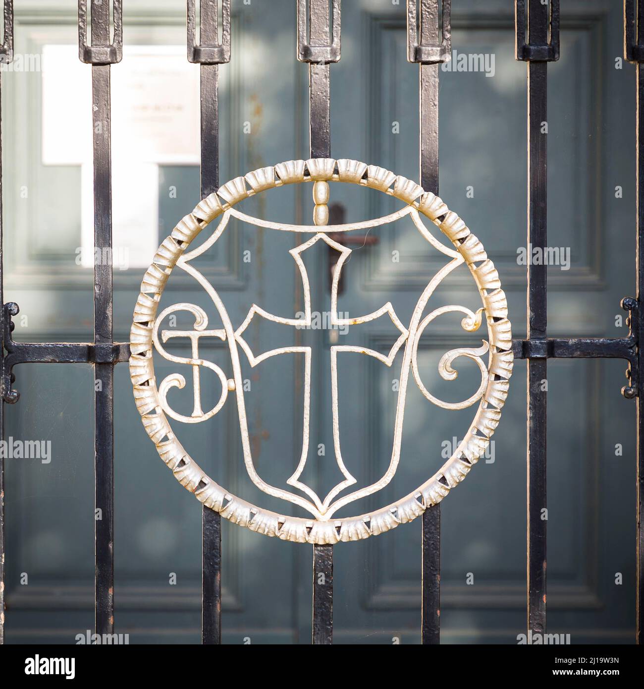 Coat of arms and initials of St. wroughtiron gate in front of