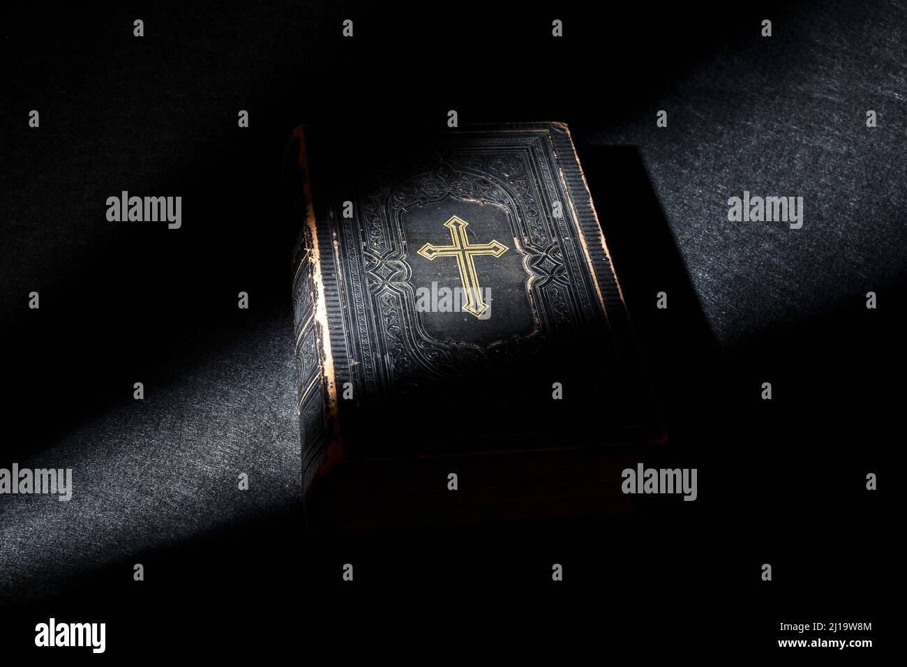 Old Bible, book on black background, grazing light Stock Photo