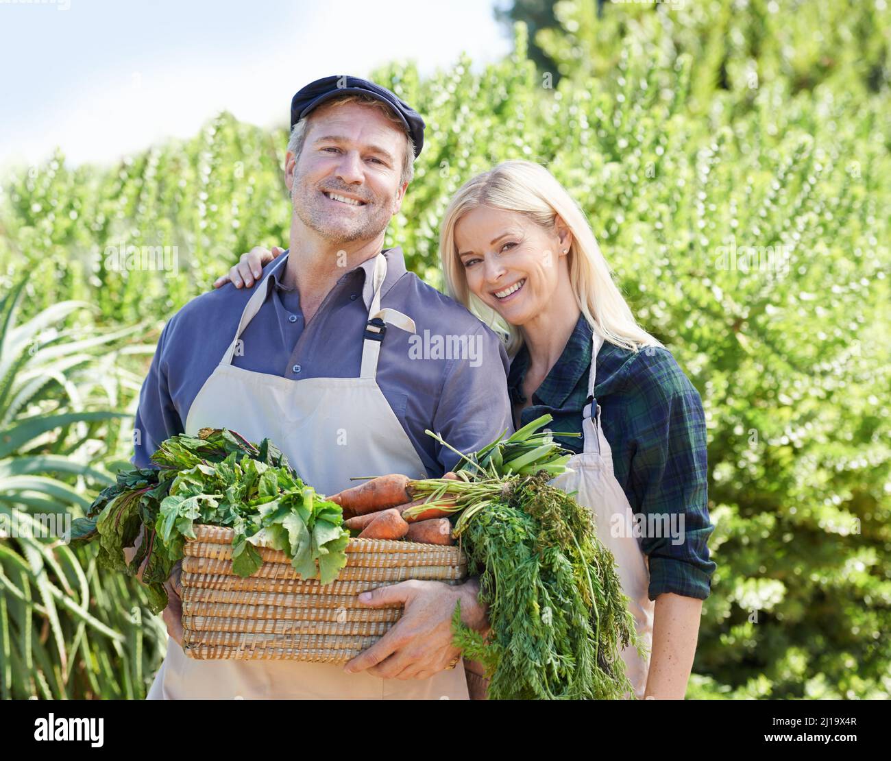 Proud of their produce. A mature farmer couple holding a basket of freshly picked vegetables. Stock Photo