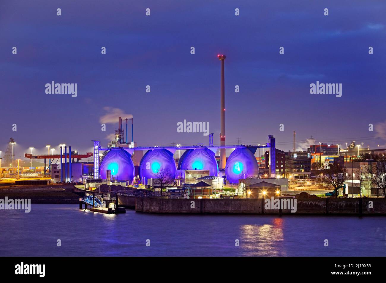 Blue illuminiete Koehlbrandhoeft sewage treatment plant in Hamburg harbour in the evening, Hamburg, Germany Stock Photo