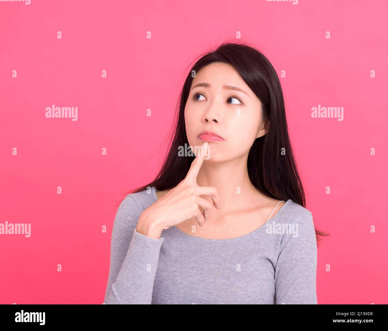 Asian young woman  look empty space and thinking idea isolated on pink background Stock Photo