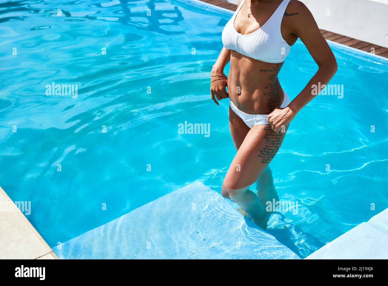 A dip in the pool will make all your worries go away. Cropped shot of an unrecognizable woman standing in a swimming pool. Stock Photo