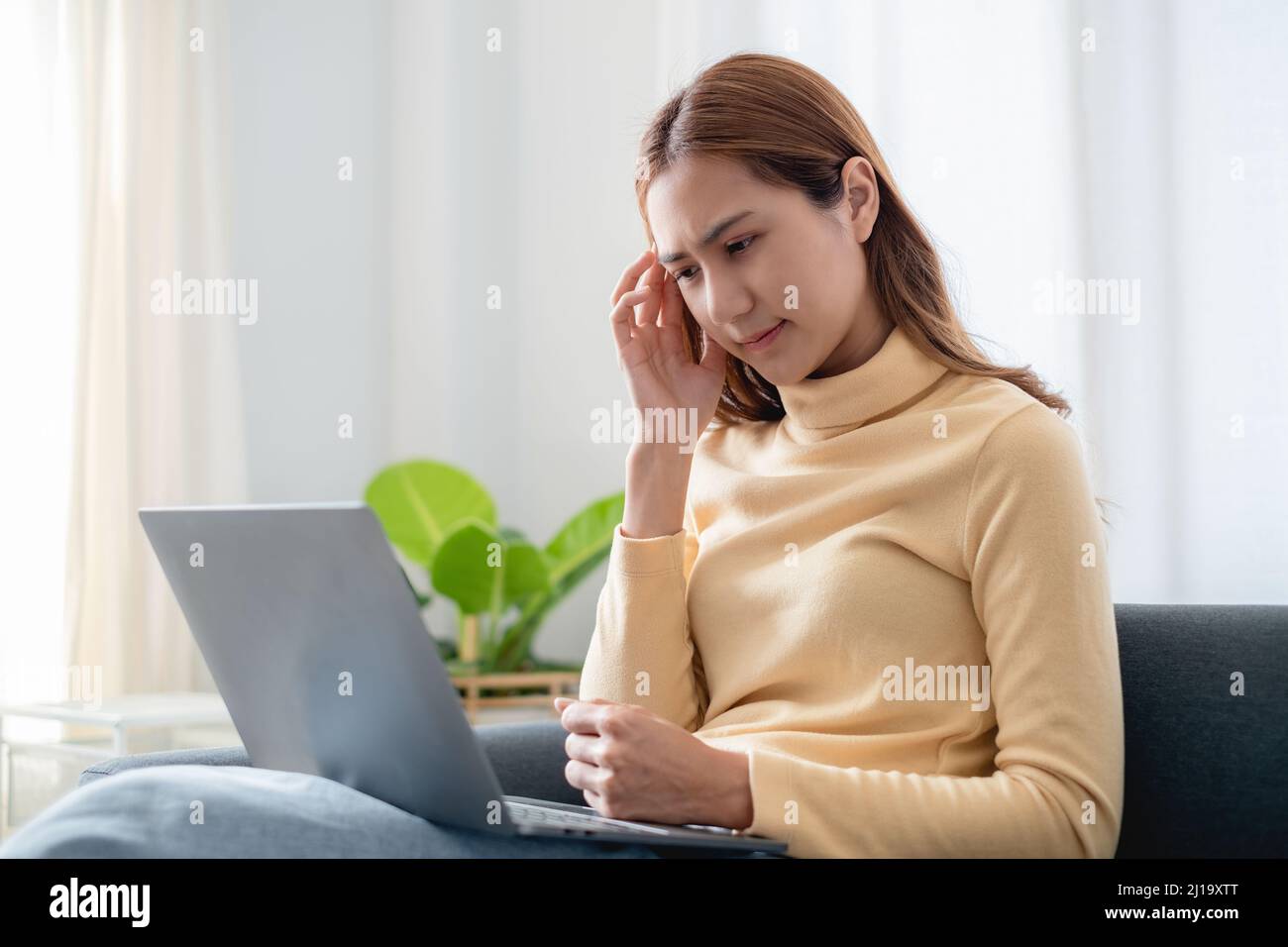 Frustrated stressed business woman sitting on sofa at home. Stock Photo