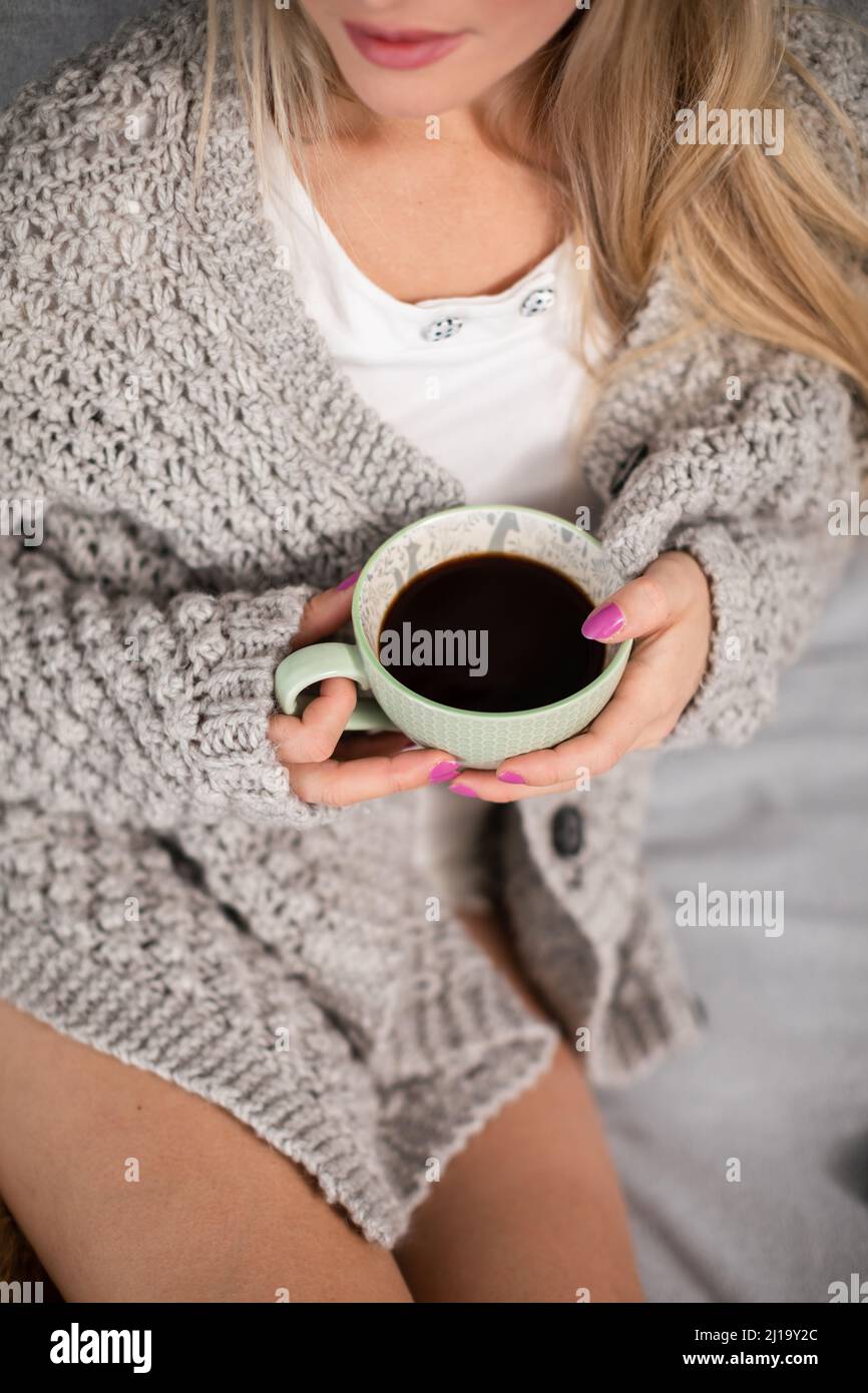 A young woman with a porcelain cup of coffee in her hands. Stock Photo