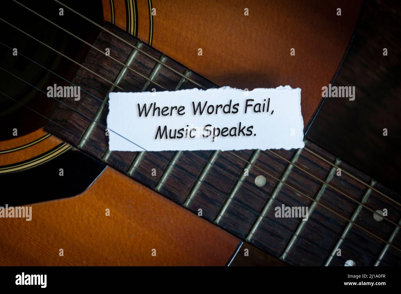 Top view of text on torn paper - Where words fail, music speaks with guitar background. Motivational concept Stock Photo