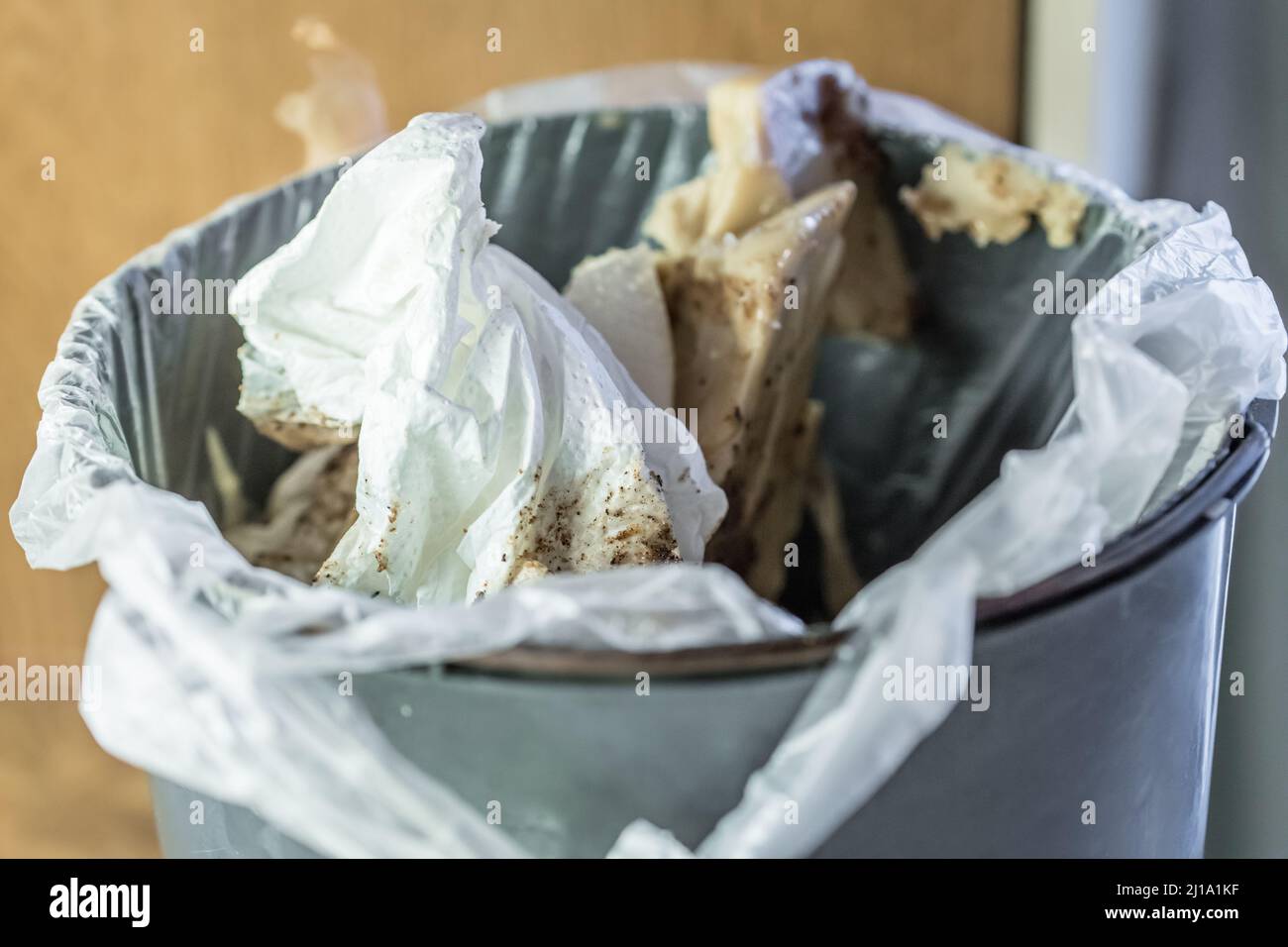 Close up of full trash can with paper and kitchen waste in plastic bag