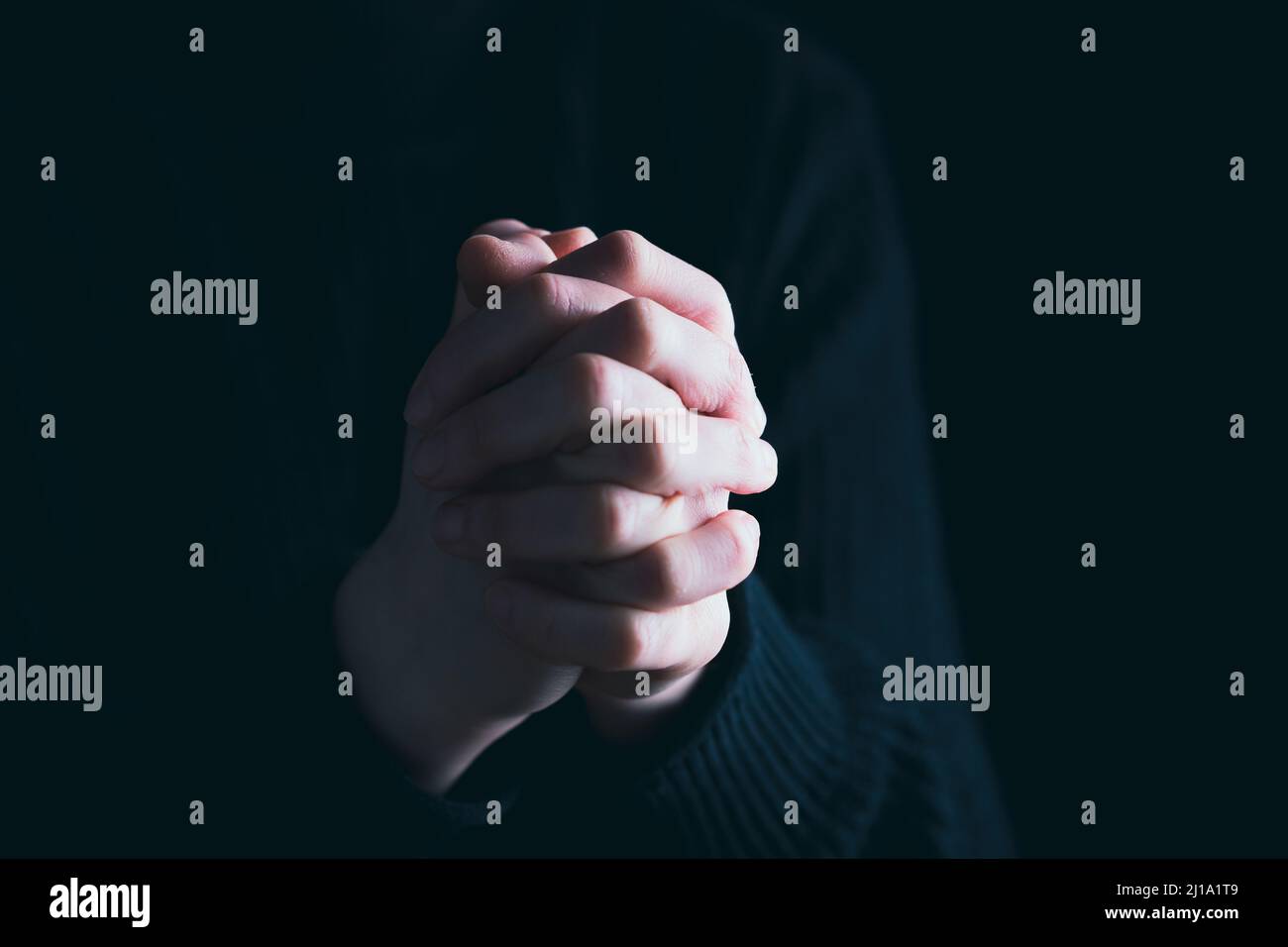 Praying hands with faith in religion and belief in God on dark ...