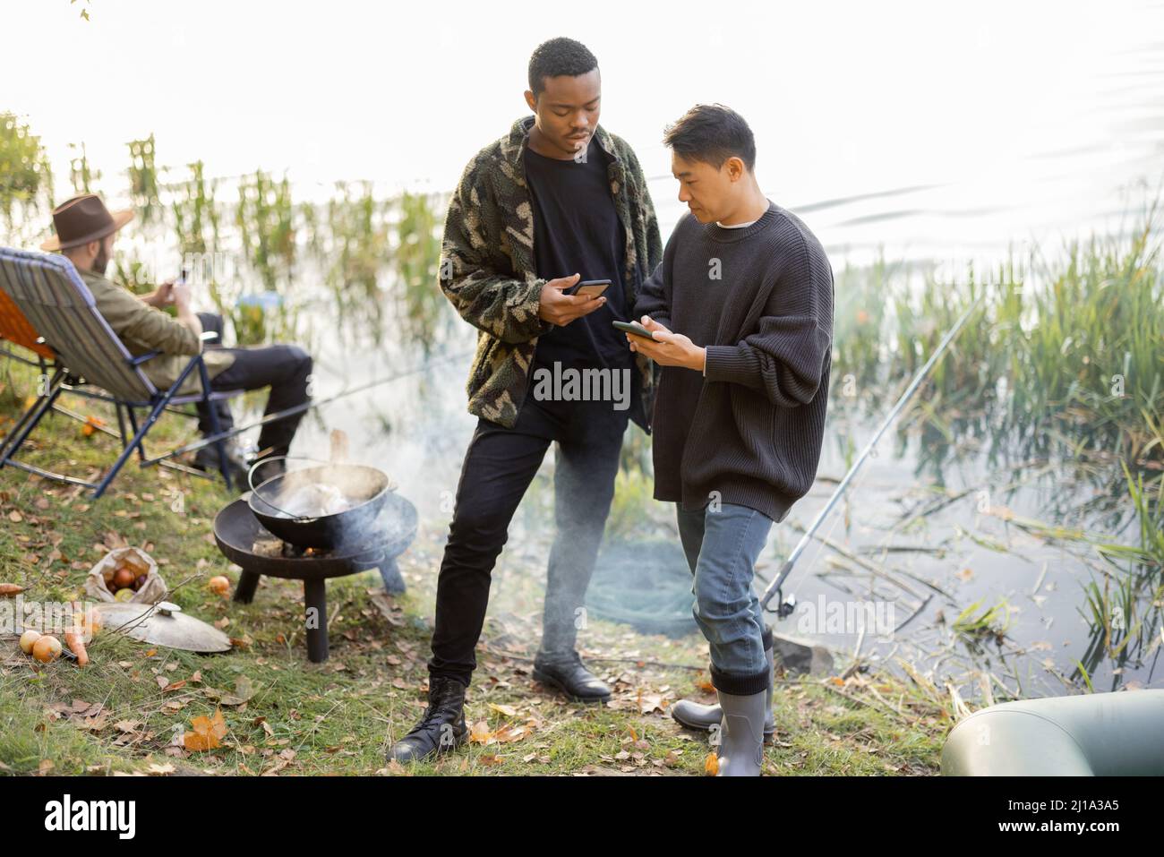 Men using smartphones during resting on pond coast Stock Photo