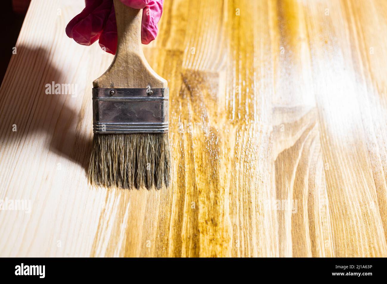 wooden board is covered with wood stain by paint brush close up at home Stock Photo