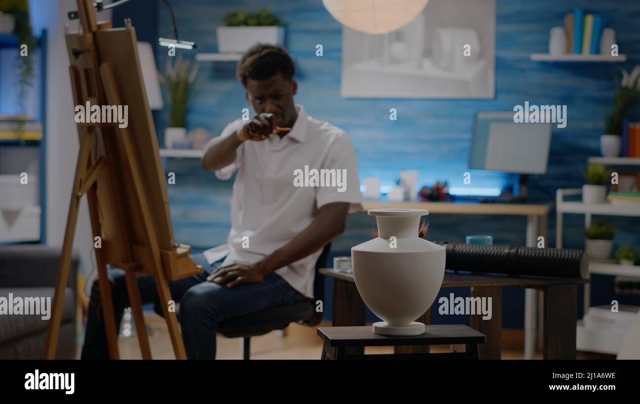Black young man drawing vase for creative project in artwork space