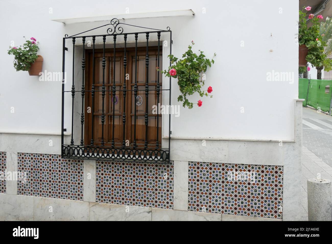 Window with iron grill flanked by two wall mounted flower pots in Andalusian village Stock Photo