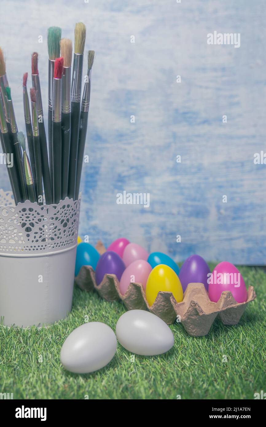 Colored Easter eggs in egg on grass with paint brushes Stock Photo