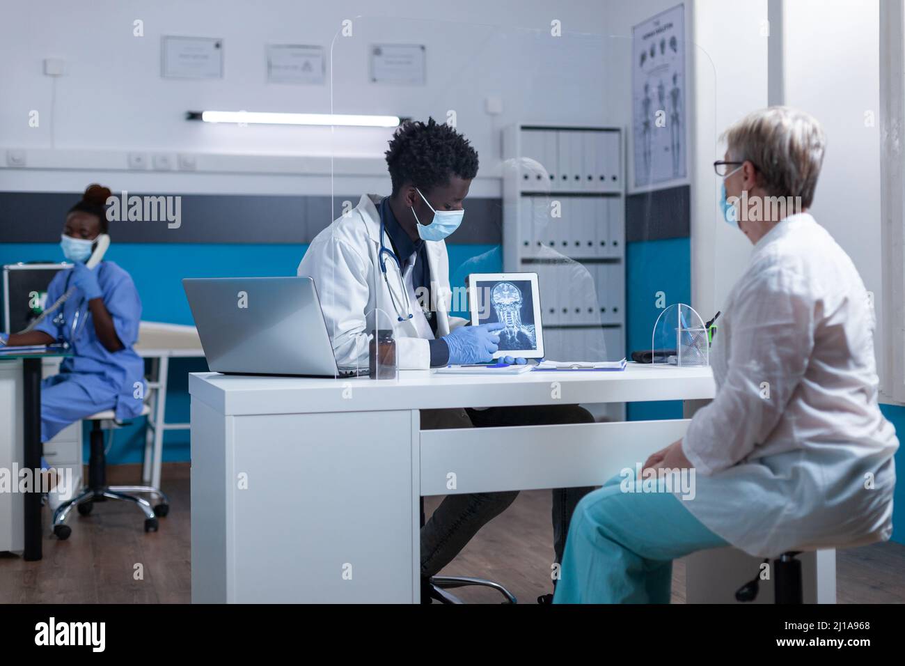 Radiology specialist explaining x-ray scan image to elderly patient in healthcare facility doctor cabinet. Radiologist talking with senior woman about scan results and consultation diagnostic. Stock Photo