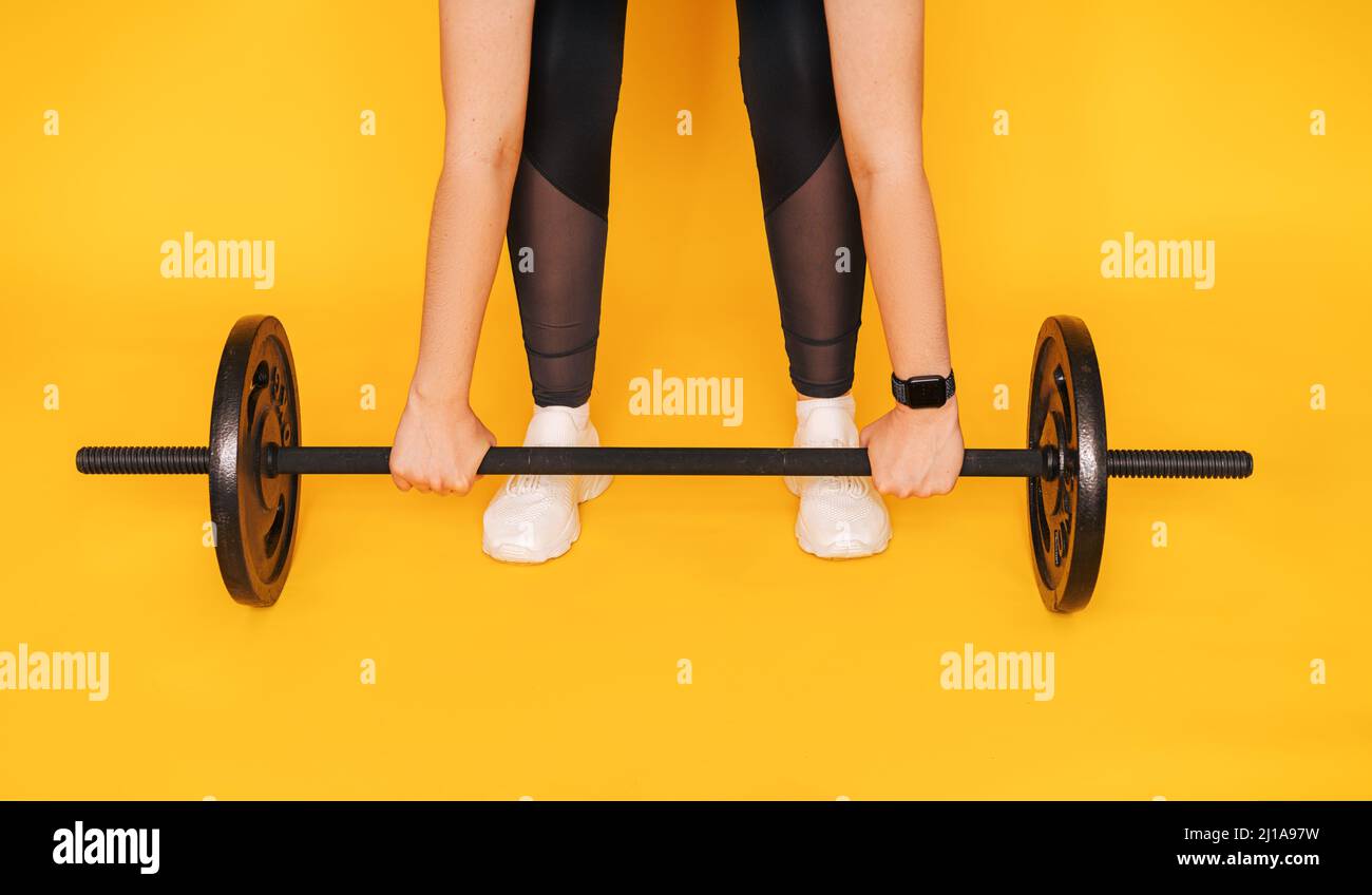The girl grabbed the bar with her hands against yellow background Stock