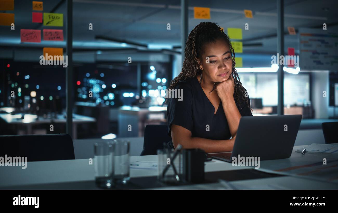 Portrait of African American Businesswoman Working on Laptop Computer in Big City Office Late in the Evening. Female Executive Director Managing Digit Stock Photo