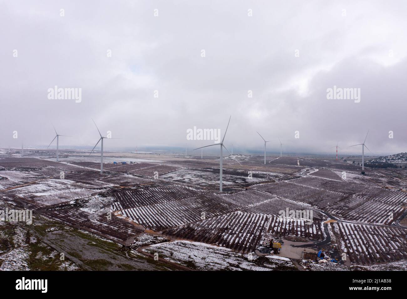 Wind turbine in a snowy landscape with early winter morning mist. Stock Photo