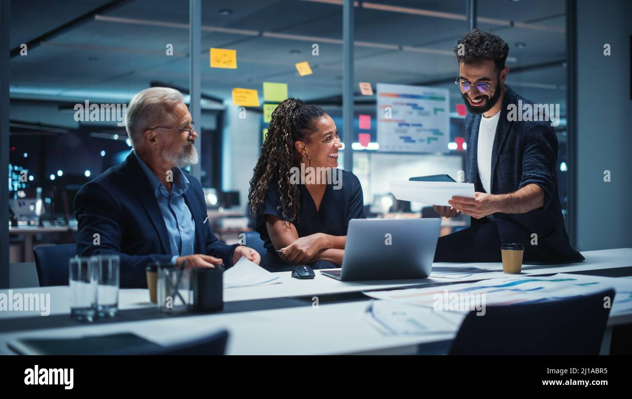 Office Conference Room Meeting: Diverse Team of Top Managers Talk; Brainstorm; Use Laptop Computer. Business Partners Discuss Financial Reports; Plan Stock Photo