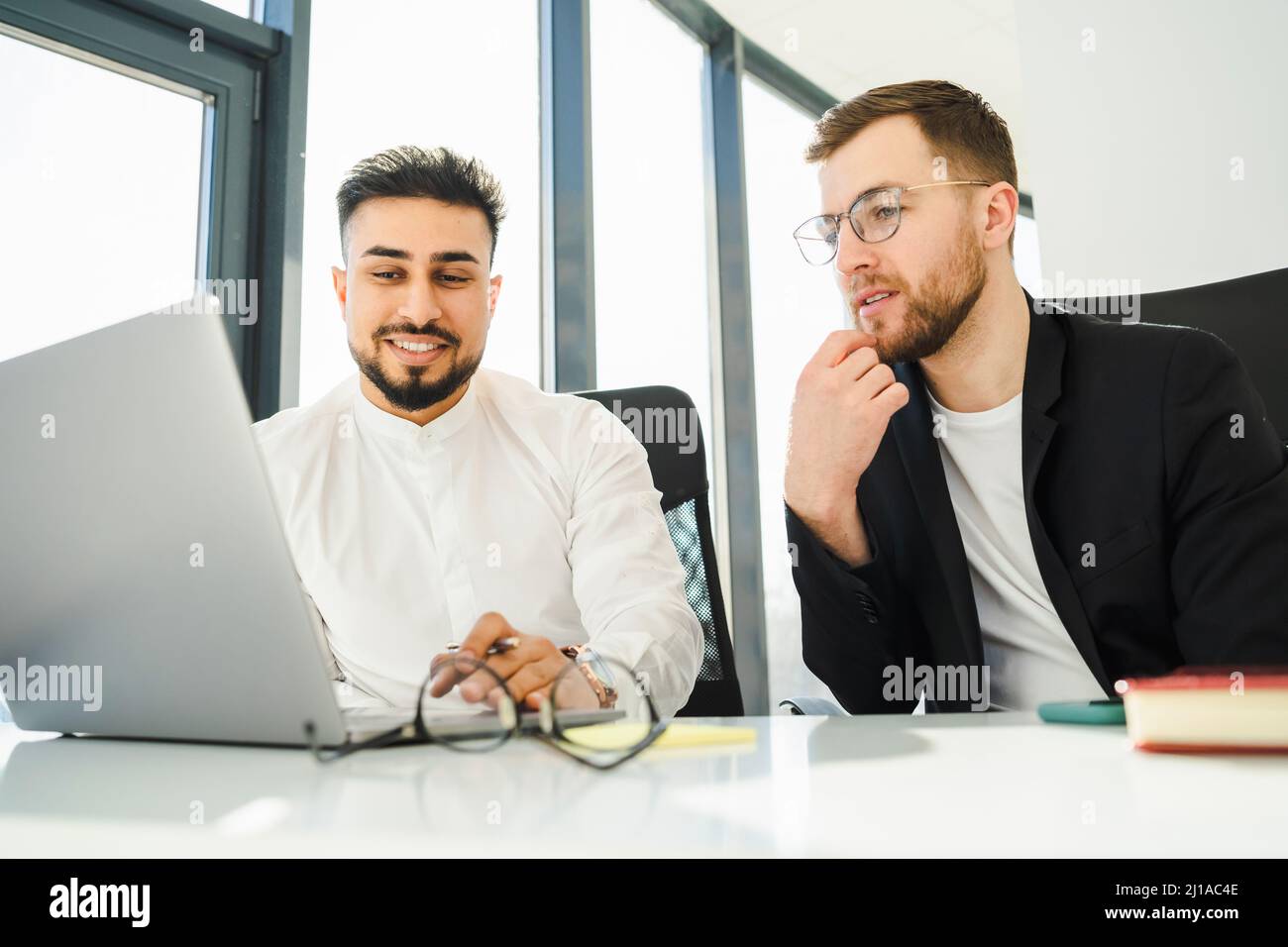 Two office workers are thinking about a new project while sitting at a laptop Stock Photo