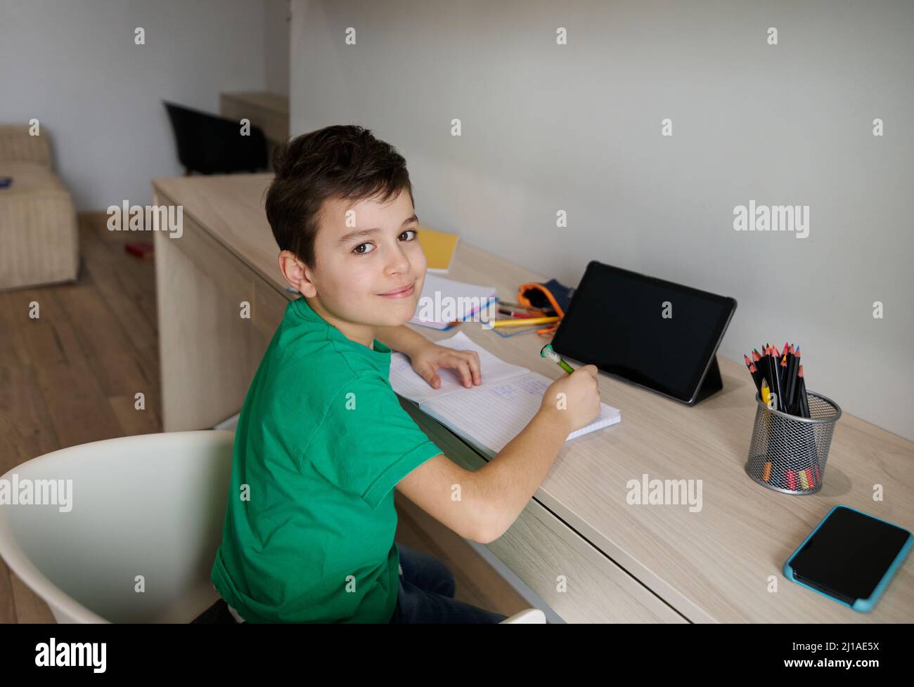 Handsome Caucasian 9 years old smart school boy sits at wooden