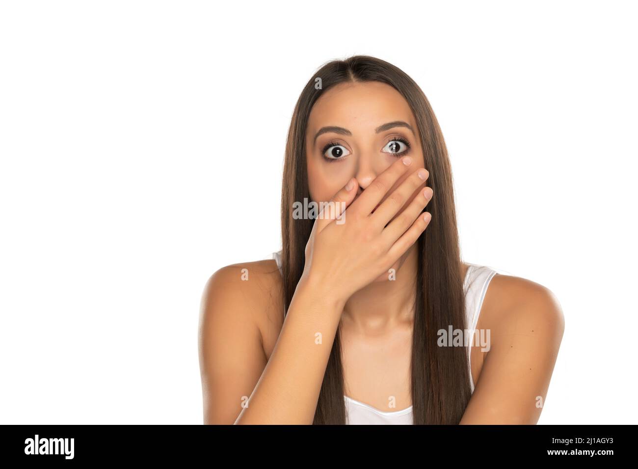 Shocked young woman covers her mouth with her hands on a white background Stock Photo